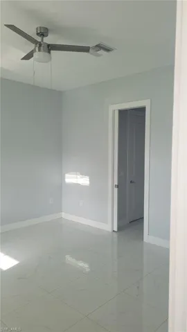Contemporary interior space featuring light-toned walls, white baseboards, and large format polished tile flooring