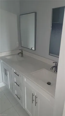 White shaker cabinetry with brushed nickel hardware, dual undermount sinks, and a light-toned countertop
