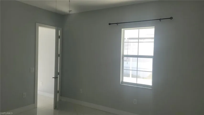 Bright interior room featuring a large window with horizontal and vertical mullions, a dark-toned curtain rod, and light gray wall paint