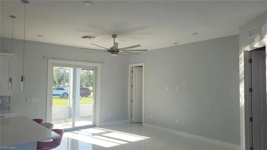 Open living space featuring large sliding glass doors, a modern ceiling fan, recessed lighting, and light-toned tile flooring