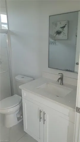 White vanity with a light-toned countertop, under-mount sink, and modern faucet