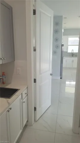 White paneled interior door opening to a space featuring large format white tile flooring with subtle veining