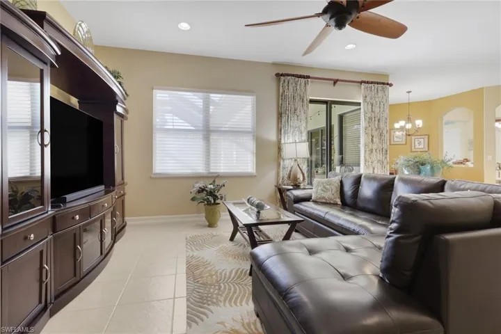 Living area featuring a chandelier, ceiling fan, light tile patterned floors, arched walkways, and recessed lighting