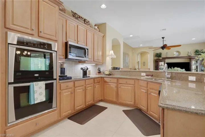 Kitchen with appliances with stainless steel finishes, light brown cabinets, light stone countertops, ceiling fan, and recessed lighting