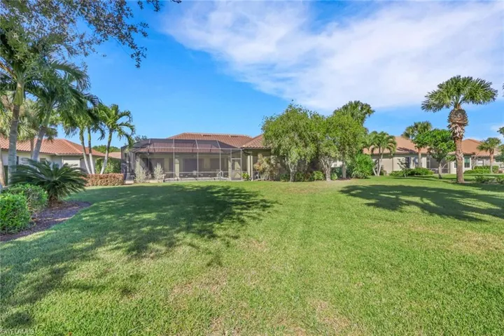 View of green lawn with a sunroom and glass enclosure