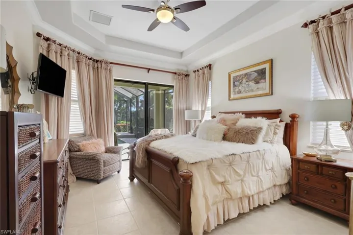 Bedroom with access to outside, a raised ceiling, light tile patterned flooring, ceiling fan, and crown molding