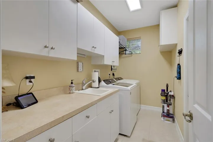 Washroom with cabinet space, light tile patterned flooring, and washing machine and clothes dryer