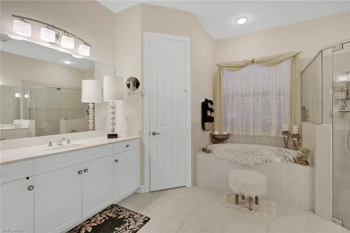 Bathroom with a shower stall, vanity, light tile patterned floors, and a garden tub