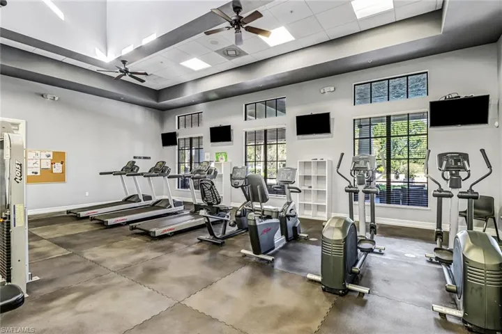Gym featuring a towering ceiling, a ceiling fan, and a drop ceiling