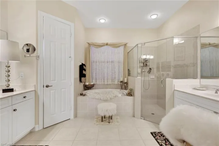 Full bathroom with vanity, a garden tub, light tile patterned floors, and a shower stall