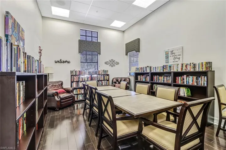 Office with a drop ceiling, dark wood-style floors, bookshelves, and a high ceiling