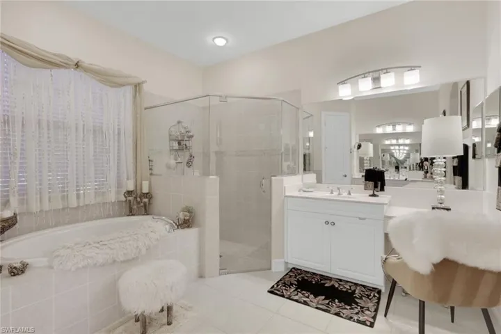 Bathroom with a garden tub, a shower stall, light tile patterned floors, and vanity