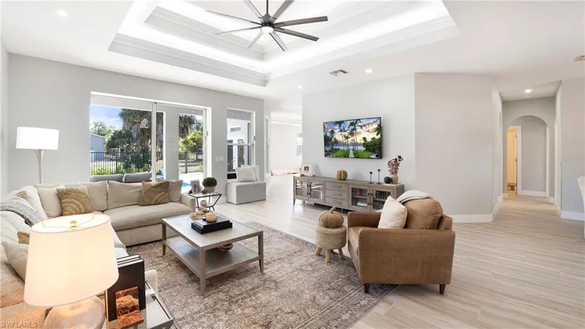 Living area with plenty of natural light, arched walkways, ornamental molding, light wood-style floors, and recessed lighting