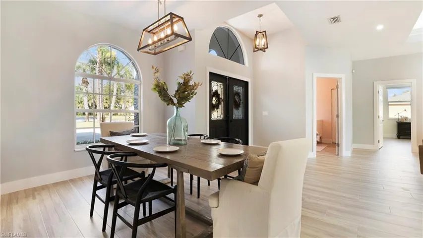 Dining space with french doors, light wood-style flooring, and a chandelier