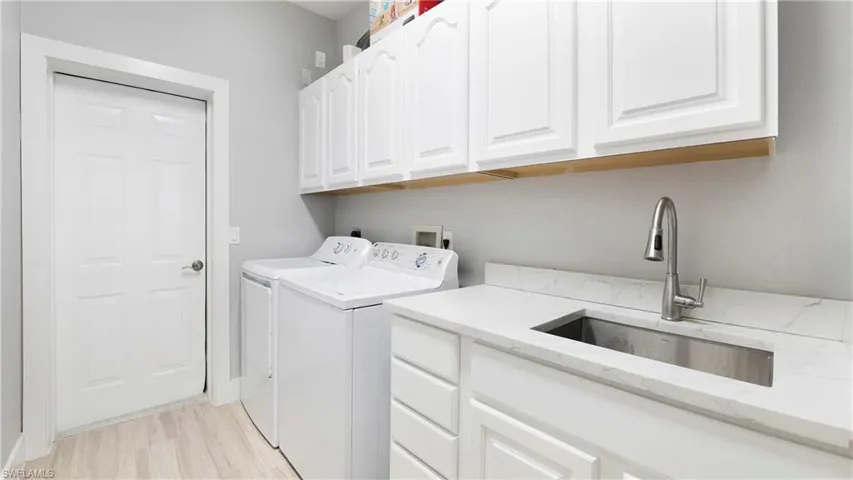 Laundry room featuring washing machine and dryer, cabinet space, and light wood finished floors