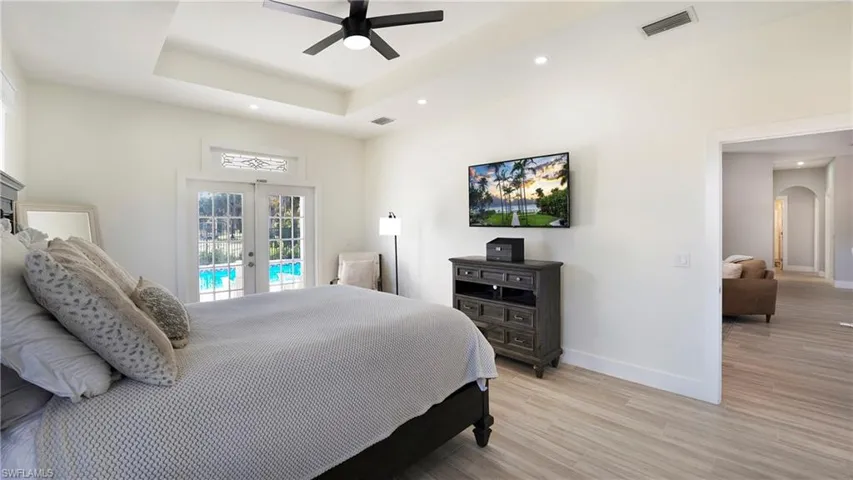 Bedroom featuring french doors, arched walkways, light wood-style floors, access to exterior, and a ceiling fan