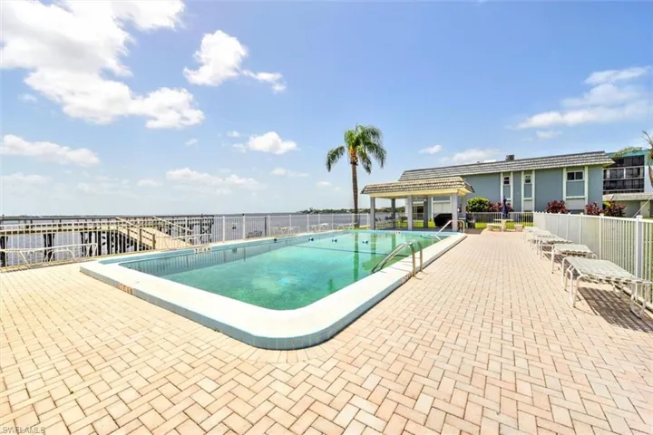 Outdoor swimming pool featuring a light blue perimeter and stainless steel handrails