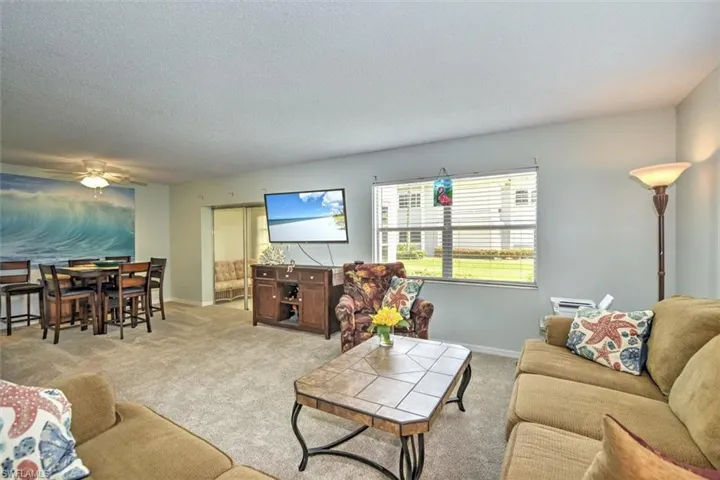 Spacious living area featuring neutral carpeting and a large window with horizontal blinds