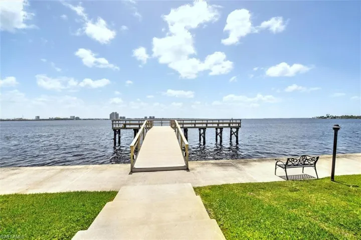 Private dock extending over calm waters with a distant city skyline
