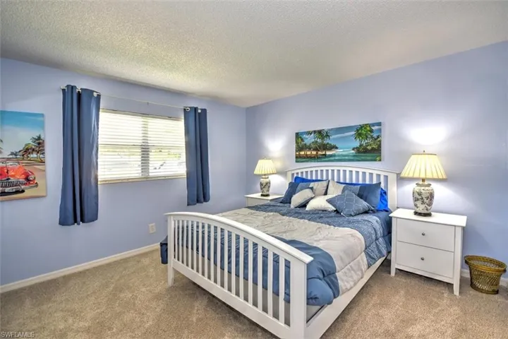 Spacious sleeping area featuring light blue wall tones, neutral carpeting, and a white framed bed