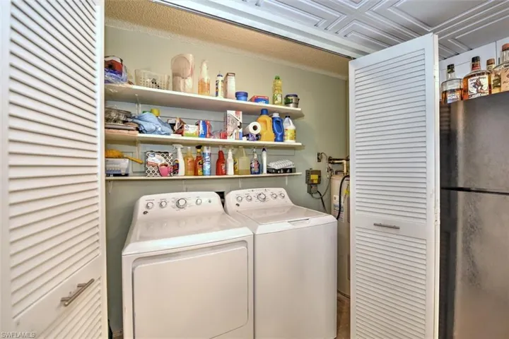 Dedicated laundry area featuring a white washer and dryer pair, wall-mounted shelving for storage, and louvered bifold doors