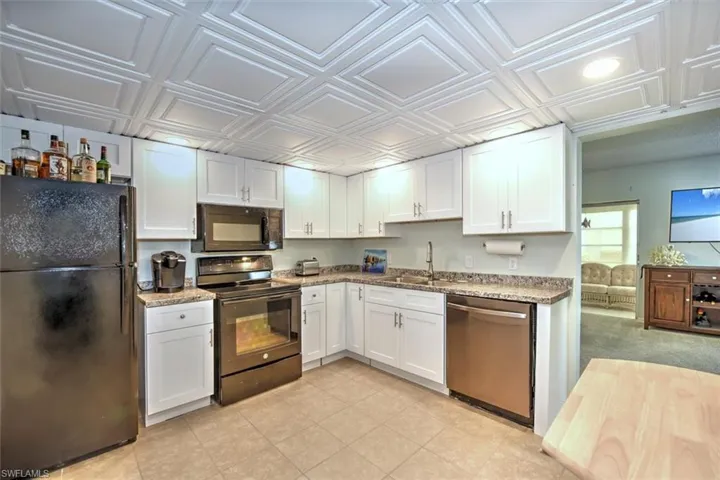 Kitchen featuring white shaker-style cabinetry, granite-style countertops, stainless steel dishwasher, black range, and black built-in microwave