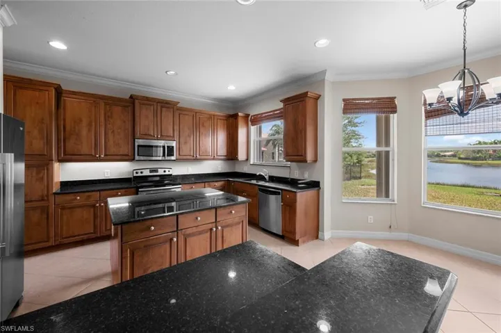 Kitchen with light tile patterned floors, crown molding, a center island, stainless steel appliances, and pendant lighting