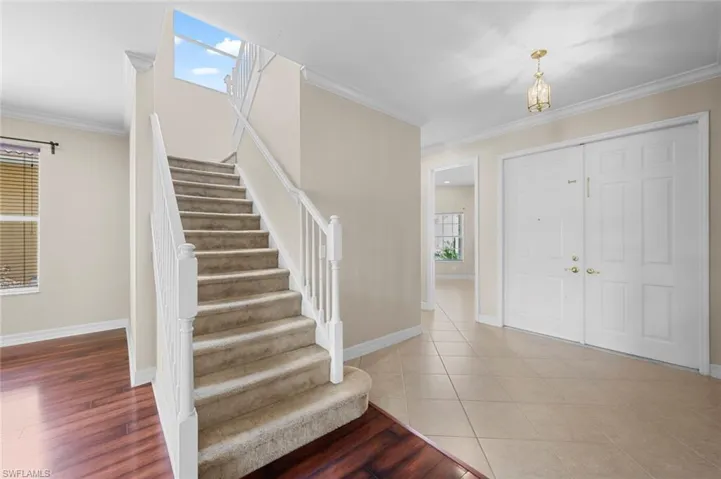 Foyer entrance with crown molding, stairway, and wood finished floors