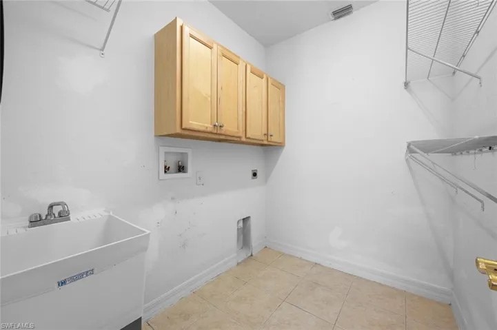 Washroom with light tile patterned flooring, washer hookup, hookup for an electric dryer, and cabinet space