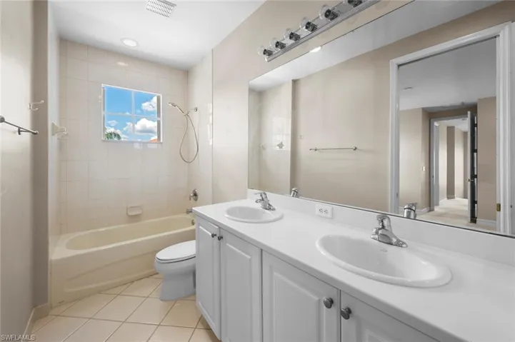 Full bathroom with double vanity, light tile patterned floors, and shower / bathtub combination