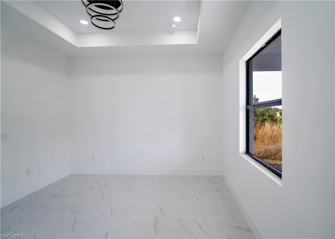 Spare room with light marble finish floors, recessed lighting, and a raised ceiling