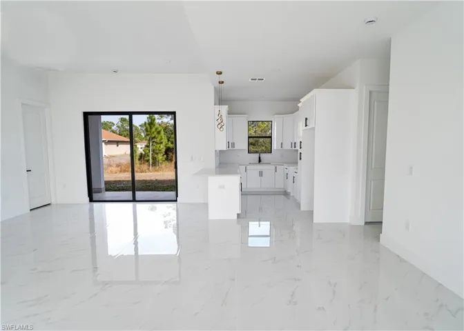 Unfurnished living room with light marble finish flooring and baseboards