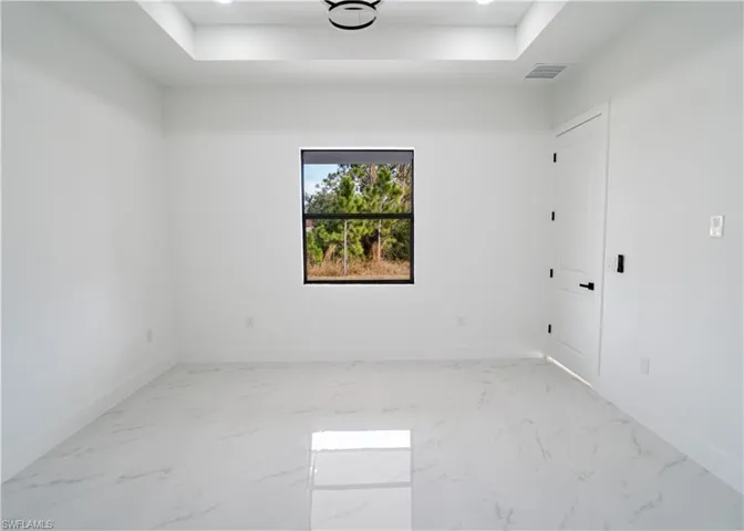 Unfurnished room with light marble finish floors, recessed lighting, and a raised ceiling