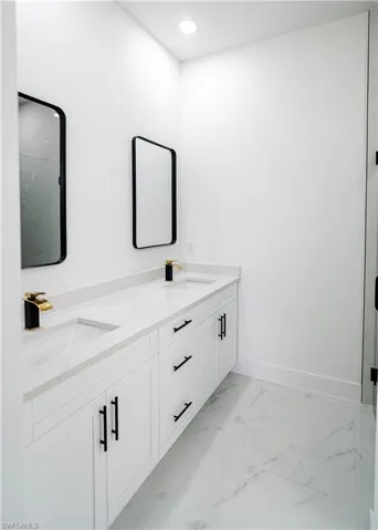 Bathroom with double vanity, a marble finish shower, light marble finish flooring, and recessed lighting