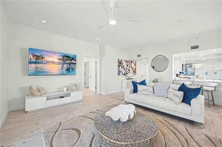 Living room with light lvt flooring, a ceiling fan, and recessed lighting