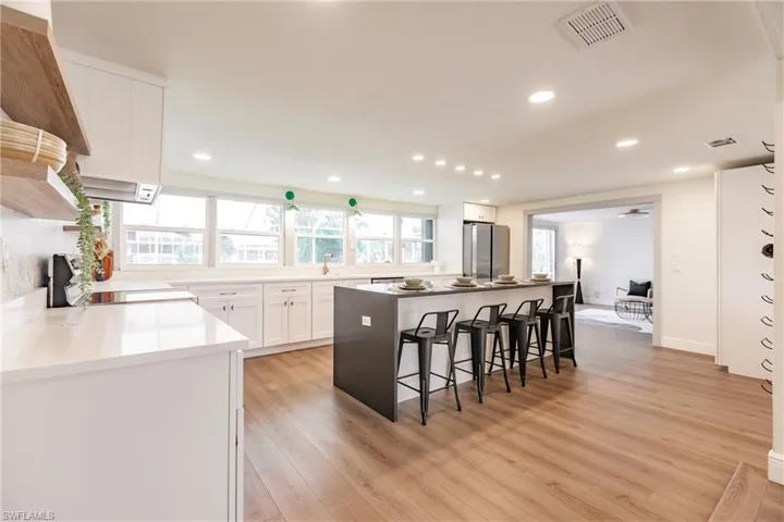 Kitchen with white cabinets, a center island, stainless steel fridge, and light wood-type flooring