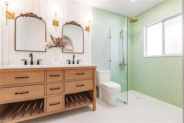 Bathroom with dual bowl vanity, tile flooring, a shower with shower door, and toilet