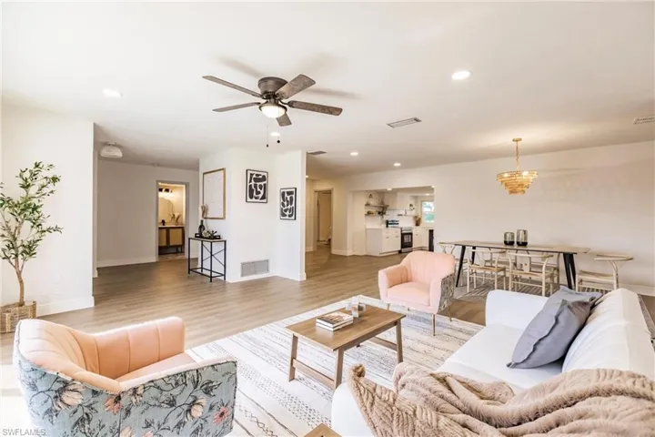 Living room with wood-type flooring and ceiling fan with notable chandelier