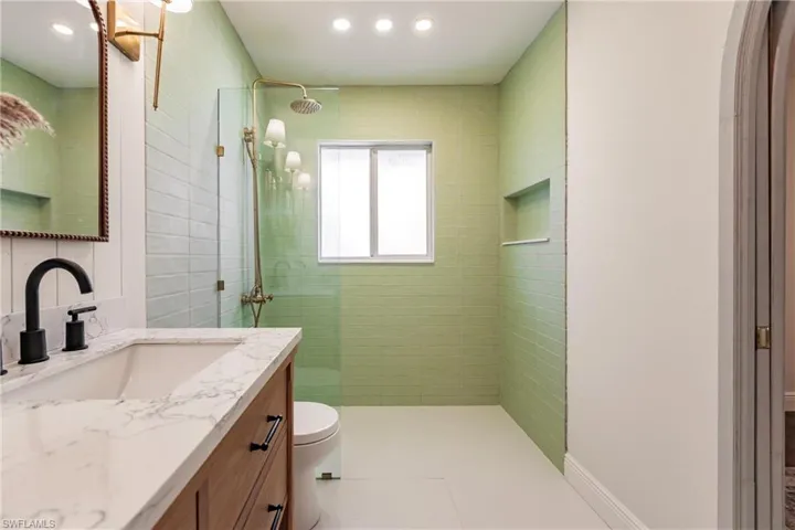 Bathroom featuring tiled shower, tile flooring, oversized vanity, and toilet