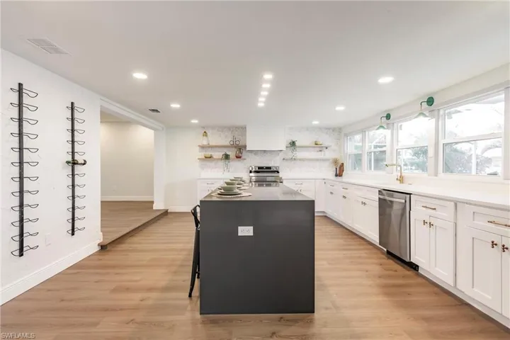 Kitchen featuring appliances with stainless steel finishes, white cabinetry, light hardwood / wood-style floors, and a kitchen island