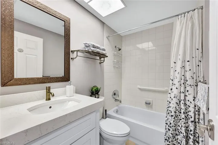 Full bathroom with shower / tub combo, a skylight, toilet, and vanity