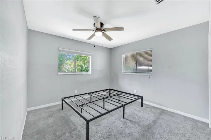 Carpeted empty room featuring ceiling fan and baseboards