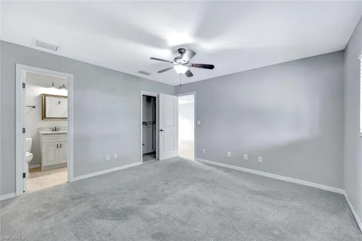 Unfurnished bedroom featuring light carpet, baseboards, a sink, and ensuite bath