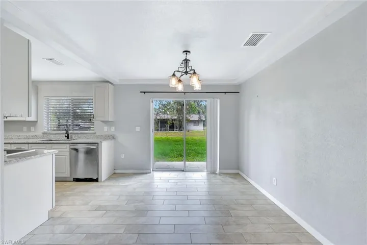 Kitchen with dishwasher, a chandelier, a sink, pendant lighting, and baseboards