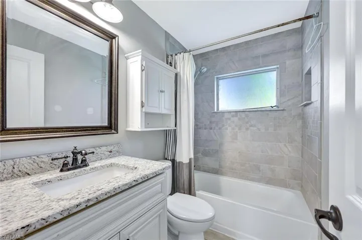 Bathroom with vanity, shower / bath combo, and toilet