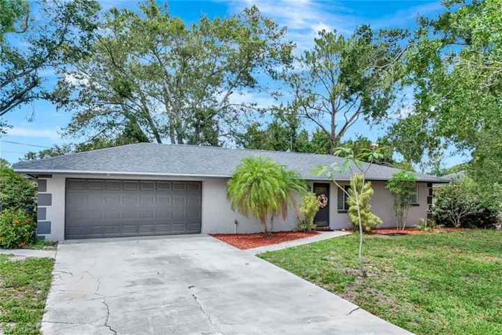 Ranch-style house with a garage, driveway, a front yard, and stucco siding