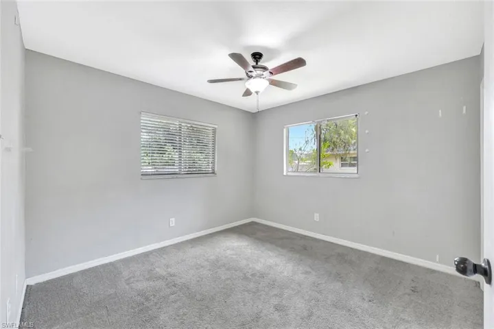 Carpeted spare room featuring a ceiling fan and baseboards