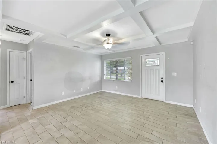 Empty room with coffered ceiling, baseboards, a ceiling fan, and beam ceiling