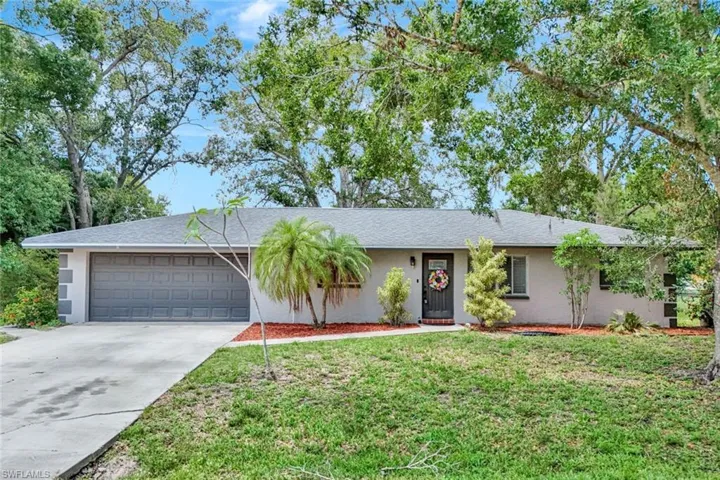 Ranch-style house featuring an attached garage, stucco siding, concrete driveway, and a front yard