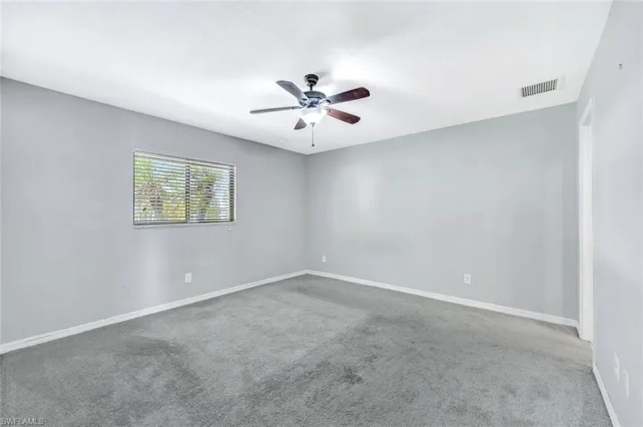 Carpeted spare room with a ceiling fan and baseboards